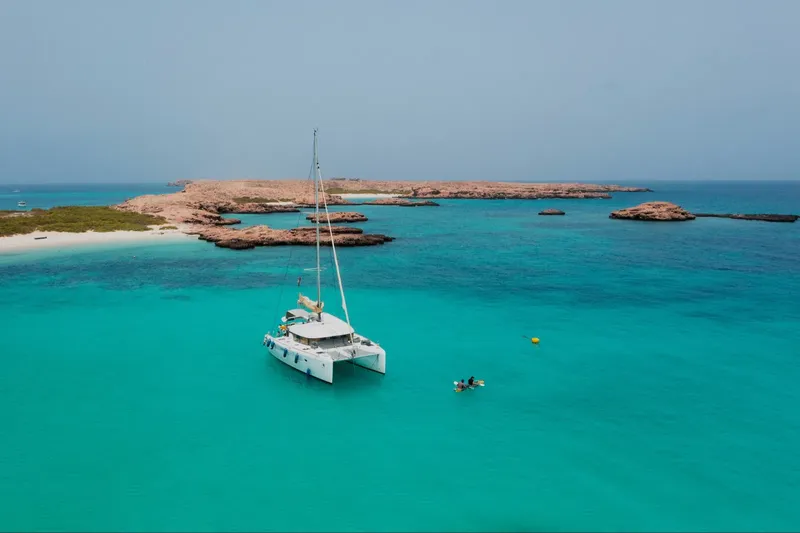 Catamaran amarré dans une eau turquoise près d'une île rocheuse