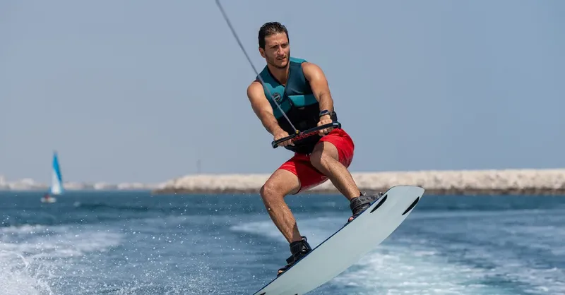 Homme pratiquant le wakeboard en mer, tiré par un bateau rapide