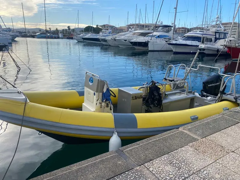 Bateau semi-rigide jaune et blanc amarré dans un port ensoleillé