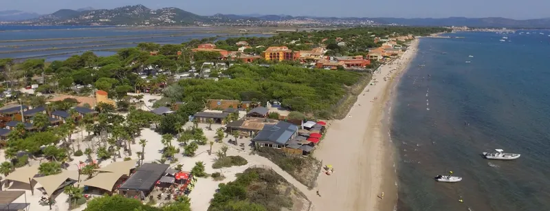 Vue aérienne d'une plage avec des bâtiments, des arbres et bateaux