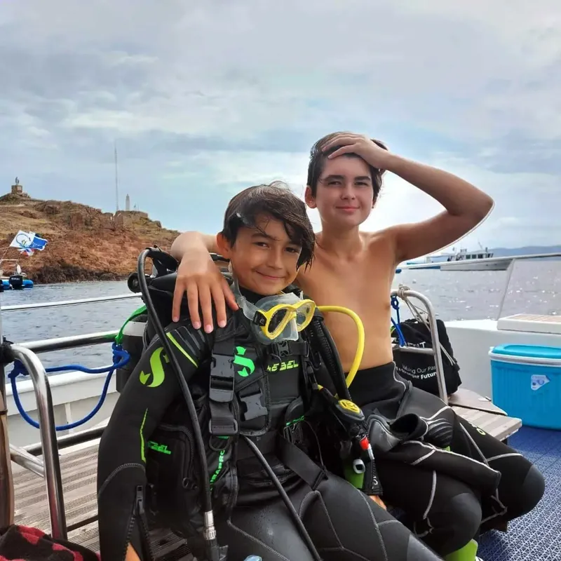 Deux jeunes plongeurs souriants équipés sur un bateau en mer