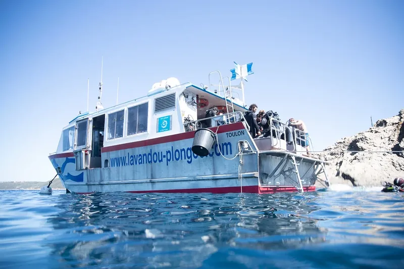 Bateau de plongée avec des plongeurs, vue mer, ciel bleu clair