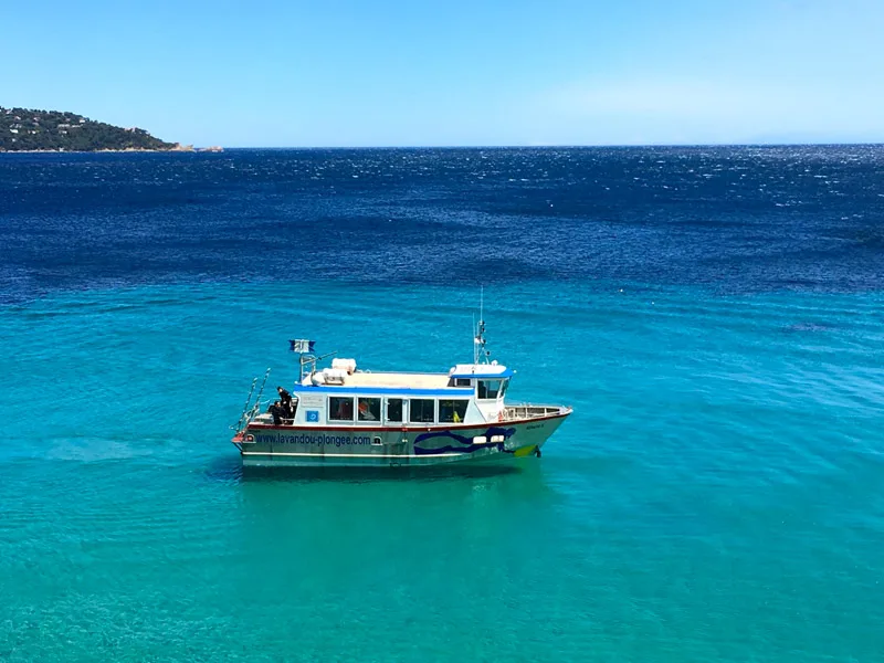Bateau de plongée bleu et blanc naviguant sur une mer turquoise claire