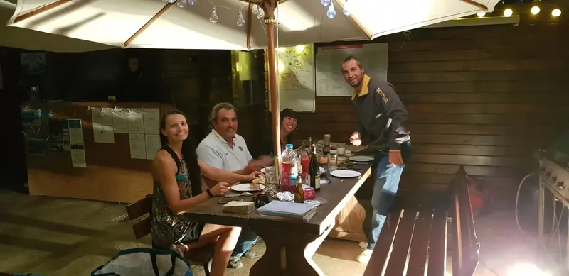 Quatre personnes sont assises et se restaurent en extérieur sous un parasol