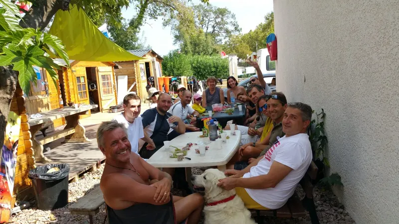 Groupe de personnes souriantes assis autour d'une table en extérieur