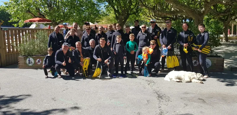 Groupe de plongeurs souriants en combinaison, prêts pour une sortie