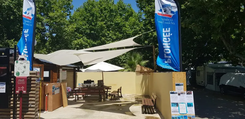 Terrasse ombragée d'un centre de plongée avec des drapeaux publicitaires