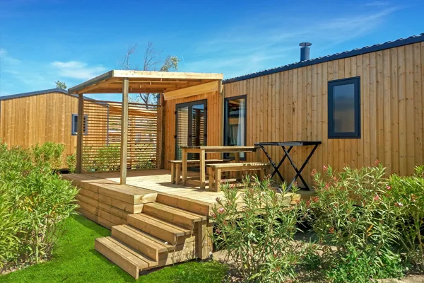 Mobil-home en bois avec terrasse et mobilier de jardin ensoleillé