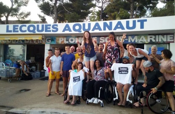 Groupe de personnes souriantes devant la facade d'un centre de plongée