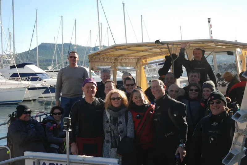 Groupe de plongeurs souriants sur un bateau dans un port ensoleillé