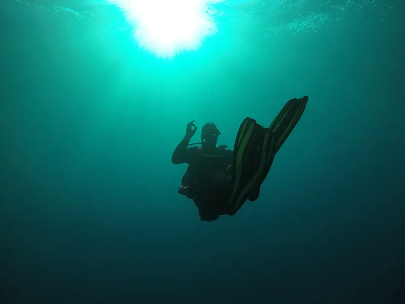 Plongeur en apnée avec signe OK, lumière du soleil filtrant l'eau