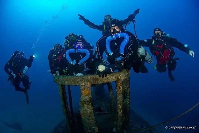 Groupe de plongeurs explore une épave sous-marine en bleu profond