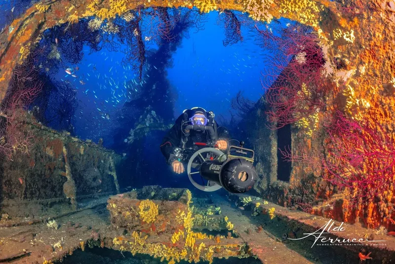 Plongeur explorant une épave sous-marine avec des coraux colorés