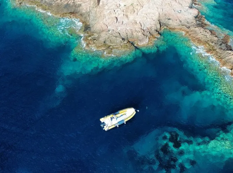 Vue aérienne d'un bateau de plongée naviguant dans une eau turquoise claire