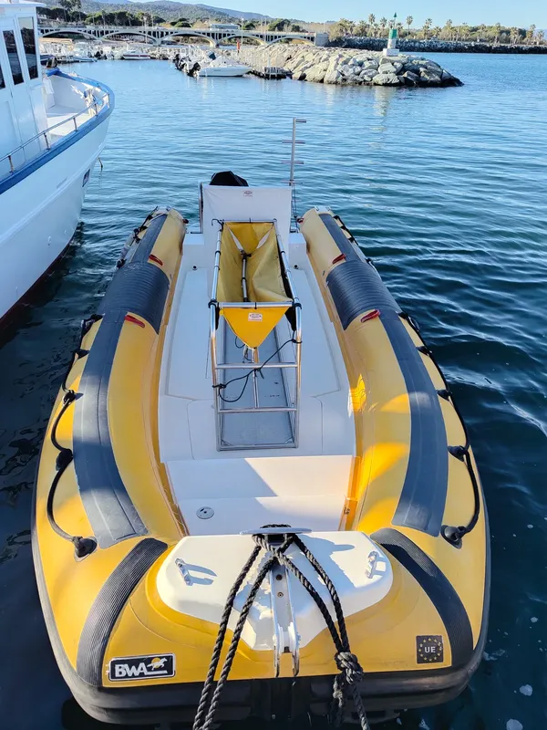 Bateau semi-rigide jaune et noir amarré dans un port ensoleillé