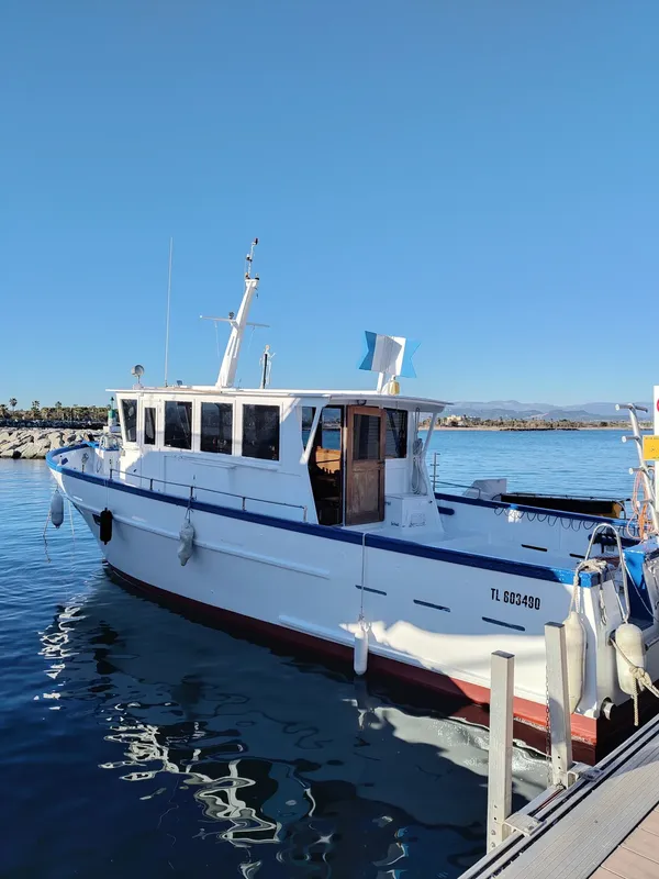 Bateau de plongée amarré dans un port ensoleillé avec ciel bleu