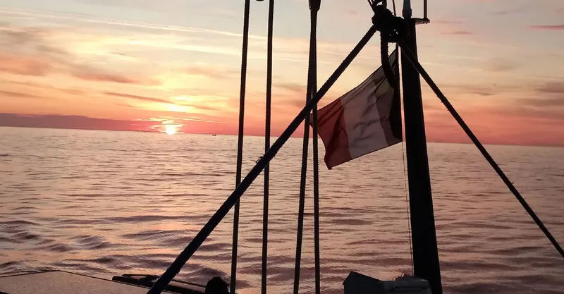 Coucher de soleil sur la mer avec un drapeau flottant au vent