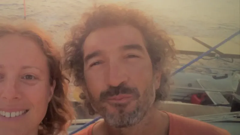 Deux personnes souriantes sur un bateau en mer, lumière dorée
