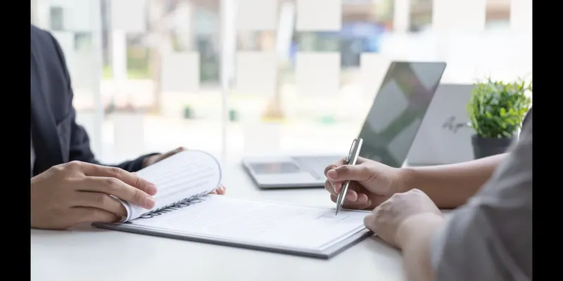 Deux personnes signent des documents sur une table de bureau