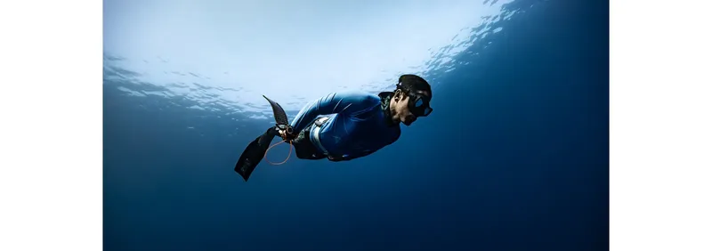 Apnéiste en pleine descente sous l'eau, nageant dans le bleu profond