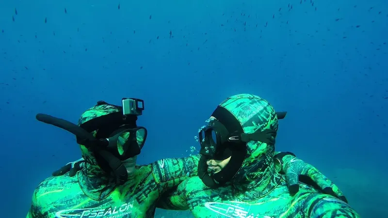 Deux plongeurs en apnée se regardent dans l'eau bleue claire