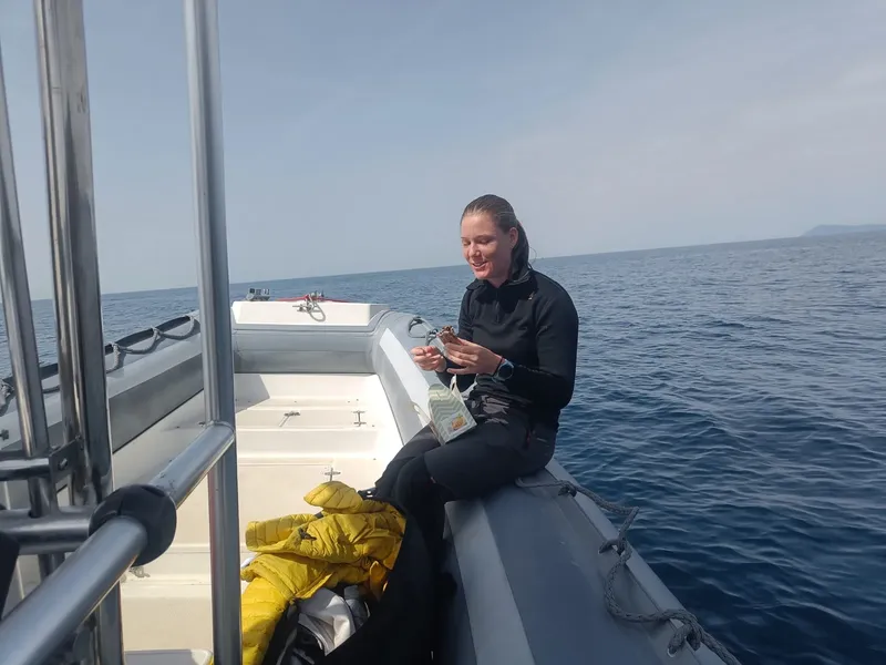 Plongeuse souriante manipule un objet sur un bateau en mer