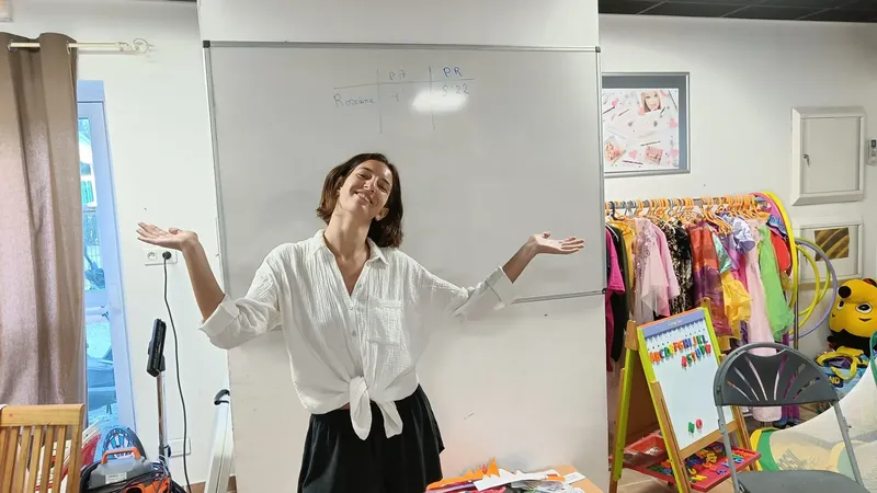 Femme souriante devant un tableau blanc dans une salle colorée