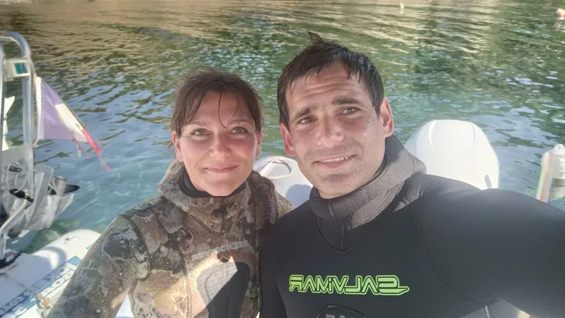 Deux personnes souriantes en combinaison de plongée sur un bateau