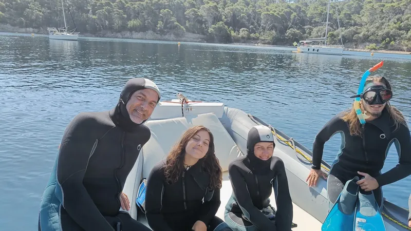Quatre personnes en combinaisons de plongée sourient à bord d'un bateau