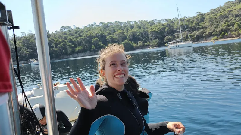 Jeune femme souriante salue depuis un bateau de plongée en mer