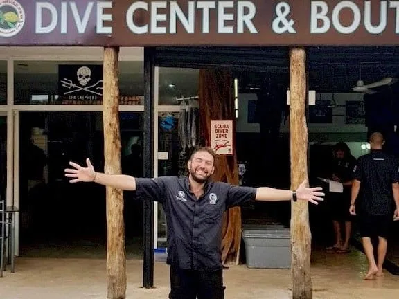 Un homme souriant devant l'entrée d'un centre de plongée