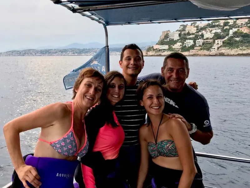Quatre personnes souriantes sur un bateau en mer, paysage côtier