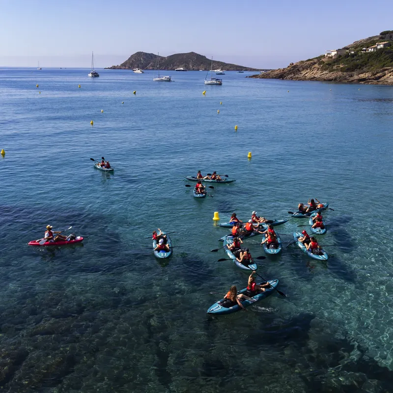 Groupe de personnes pratiquant le kayak en mer, eau turquoise, ciel bleu
