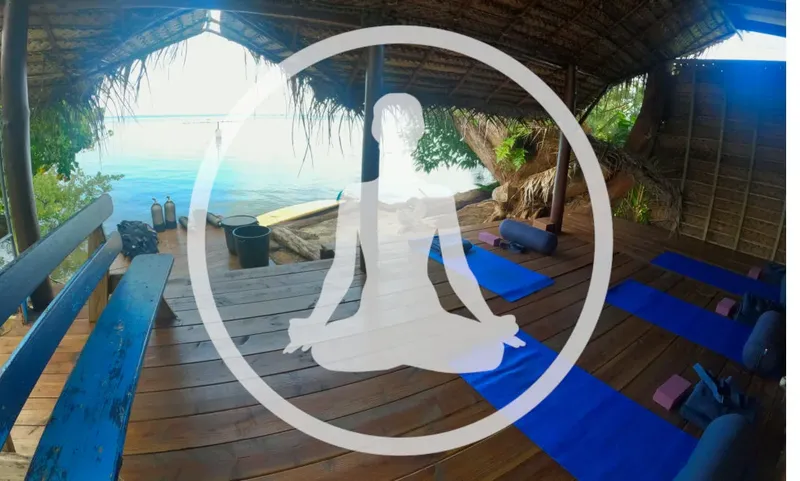 Personne en posture de yoga sur une terrasse en bois face mer