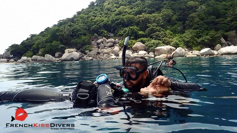Deux plongeurs équipés flottent à la surface près d'une côte rocheuse