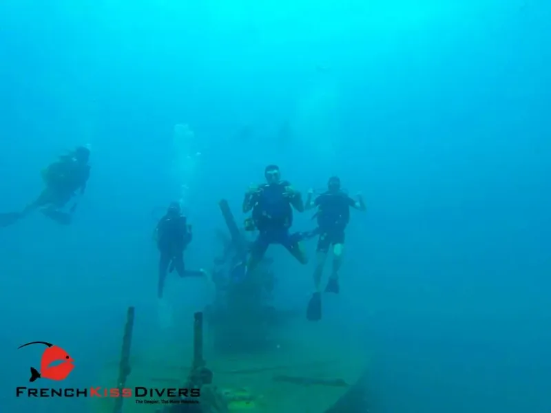 Plongeurs explorent une épave sous-marine dans une eau bleu clair