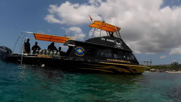 Bateau de plongée noir et jaune avec des personnes et des bouteilles