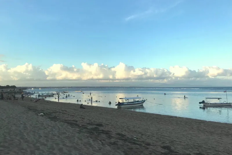 Plage avec plusieurs bateaux et des personnes dans l'eau
