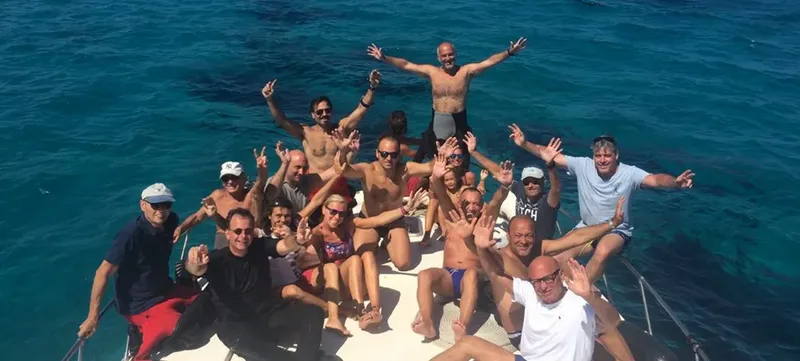Groupe de plongeurs souriants et enthousiastes sur un bateau en mer