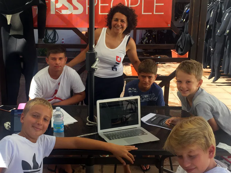 Groupe de jeunes et une monitrice regardent un ordinateur portable