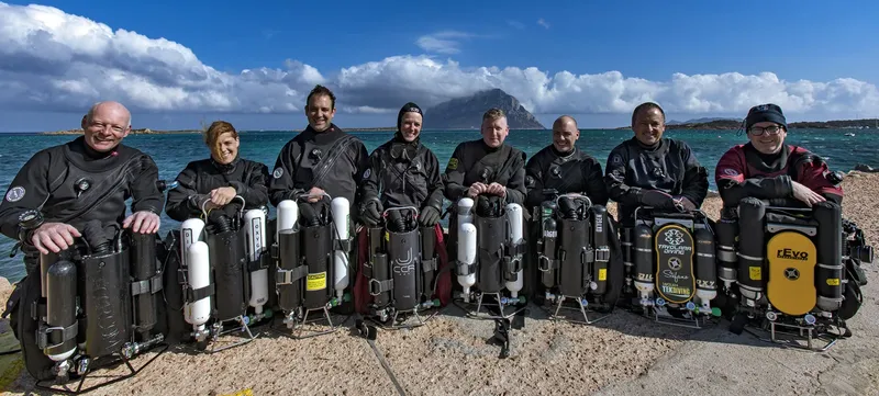 Groupe de plongeurs en combinaison sur une plage ensoleillée