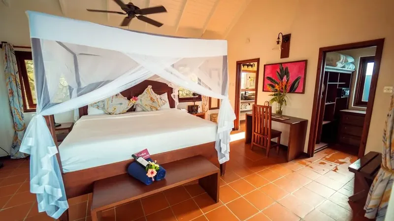 Chambre d'hôtel avec lit à baldaquin, bureau et salle de bain visible