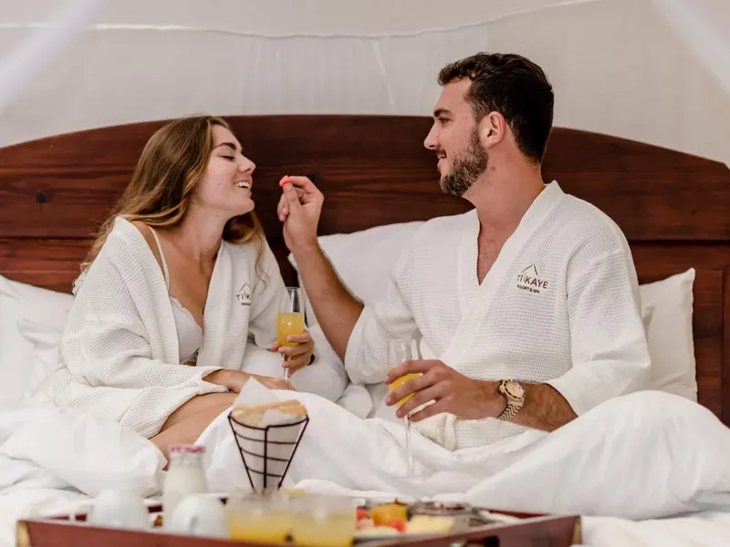 Couple souriant au lit, petit déjeuner et boissons fraîches