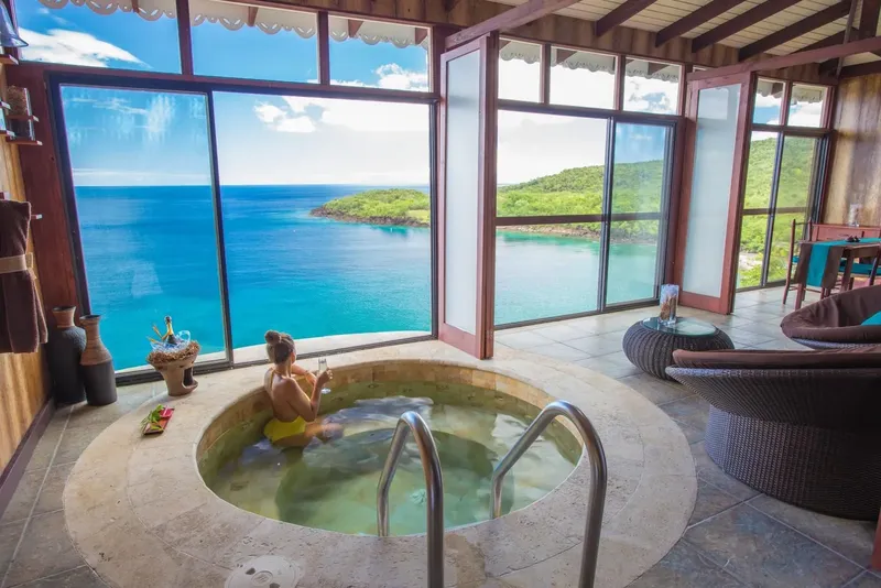 Femme dans un jacuzzi intérieur avec vue sur la mer turquoise