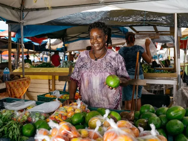 Femme souriante vendant des mangues sur un marché ensoleillé
