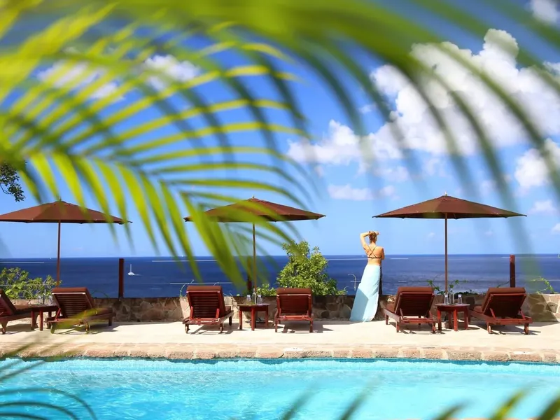 Femme regardant la mer depuis une piscine avec transats et parasols