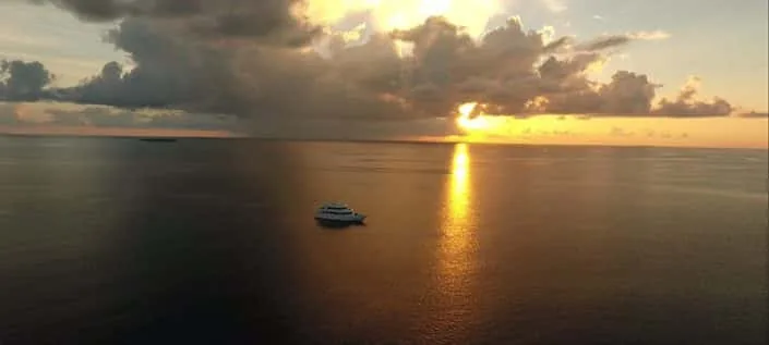 Bateau de plongée sur une mer calme au coucher du soleil