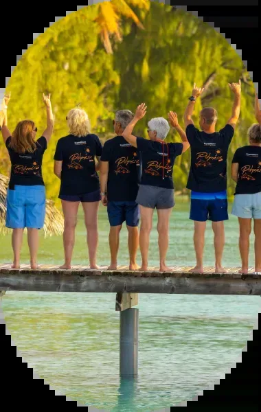 Groupe de personnes debout sur un ponton, bras levés, paysage tropical