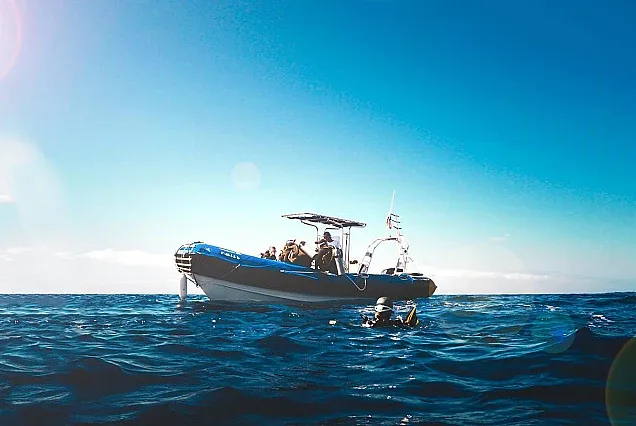 Bateau de plongée avec des passagers et un plongeur dans l'eau
