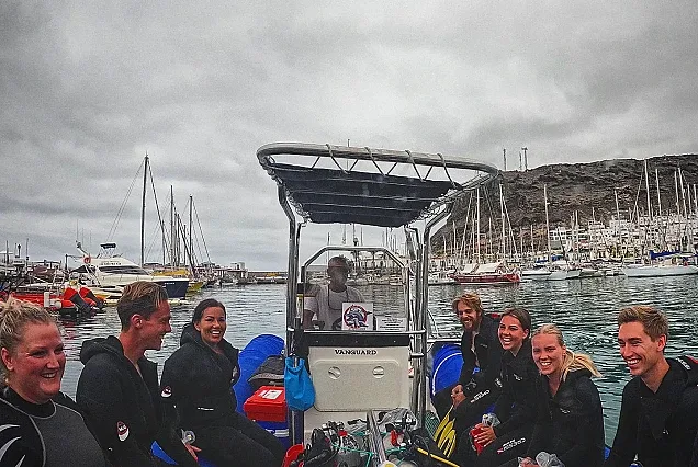 Groupe de plongeurs souriants à bord d'un bateau dans un port